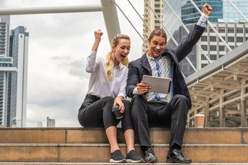 two caucasian business couple show exciting when watching table computer outdoor