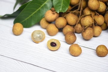 Longan fresh tropical fruit and green leaf in Thailand - Dimocarpus longan and peel exotic fruits on white wooden background