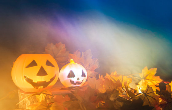 Halloween pumpkin lantern with dry leaves autumn on wood with smoke / head jack o lantern evil faces spooky holiday decorate on halloween