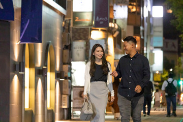 夜の繁華街を楽しそうに歩く若い男女