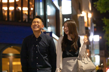 夜の繁華街を楽しそうに歩く若い男女