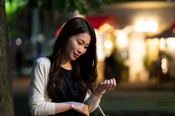 夜の町並みを背景に待ち合わせをする若い女性