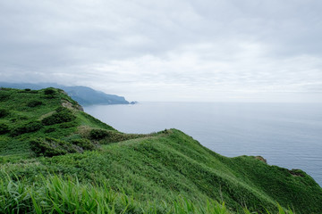 Seascape on mountain cliff view, the green hills on top view,windy with sea coastline and shore scenery,tourism trail at Cape of Kamui Island in Shakotan,Hokkaido,Japan 