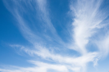 White wispy clouds, blue sky with mountain background
