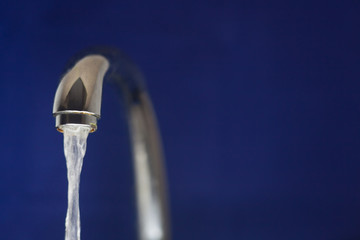 Water flows from faucet. The pressure of clean and clear water flows from an iron tap in the...