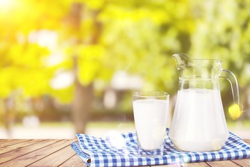 Glass of milk and jug on blurred background