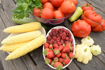 harvested vegetables. Tomatoes, corn, berries, eggplant on a wooden dark background