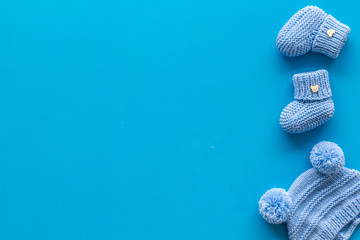 Booties and hat for newborn boy on blue background top view mockup