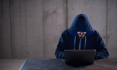 talented hacker using laptop computer while working in dark office