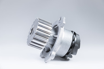 New metal automobile pump for cooling an engine water pump on a gray background with a gradient. The concept of new spare parts for the car engine