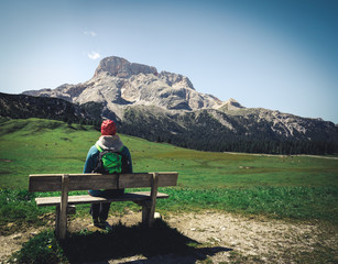 woman sitting on a wooden bench contemplating a valley in the Alps mountains. A stunning spring...