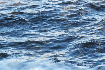 Blue river water background, waves and foam on water surface 