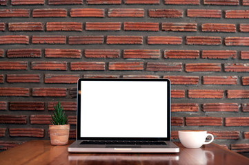 White screen Lap top on wood table with coffee cup and brick background.