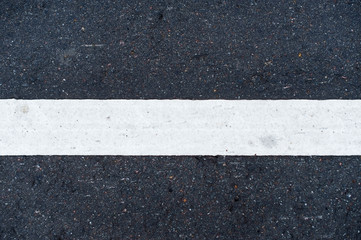 white horizontal road marking line on asphalt in the center of the image close up