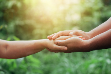 Close up of Two people holding hand together over blurred green nature garden background, Business man and woman shaking hands, helping hand and teamwork  concept with copy space - Powered by Adobe