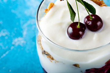 Close-up berry dessert with cherry, butter cream and granola, healthy vegetarian dessert