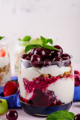vertical close - up image glass with berry Breakfast, dessert of ripe cherries, granola and ricotta cheese with copy space