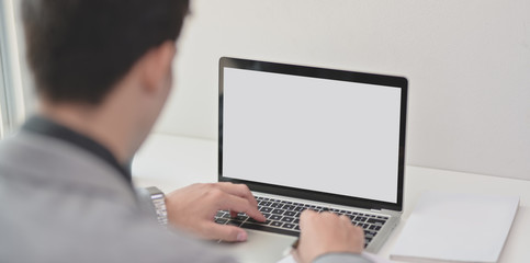 Close-up view of young businessman typing on blank screen smartphone