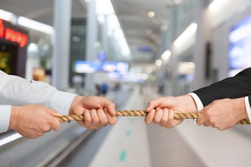 Tug war, two businessman pulling a rope in opposite directions isolated on white background