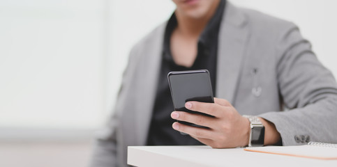 Cropped view of young businessman holding his smartphone