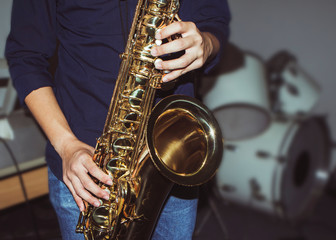 a musician plays tenor saxophone on stage with blurred music instrument background