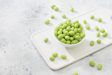 Peanuts in wasabi in a white plate on a light table