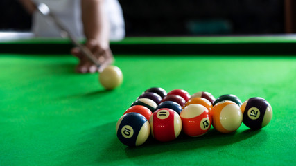 Man's hand and Cue arm playing snooker game or preparing aiming to shoot pool balls on a green billiard table.