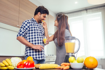 healthy and eco lifestyle.happy indian woman with her husband making smoothie in big kitchen