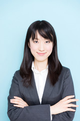 Young business woman wearing grey suitagainst light blue background