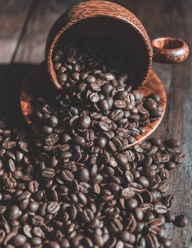 Roasted coffee beans in wood cup on wooden background