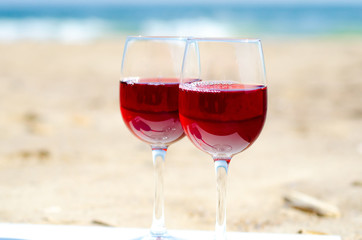 Couple of glasses with red wine on the sea beach