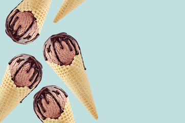 Decorative border of chocolate ice cream in crisp waffle cones with sweet brown sauce on green...