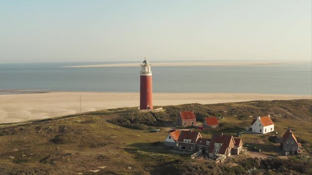 Aerial shot of the beautiful lighthouse revealing wide sand beach at the Texel island (part of Wadden islands) in The Netherlands, with Vlieland island visible in the background