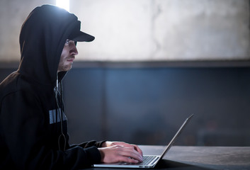 talented hacker using laptop computer while working in dark office