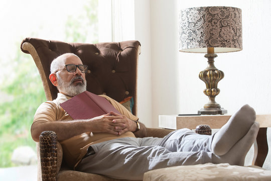 senior man sleeping while reading a book	