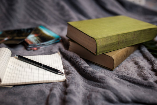 Old green books on the gray plaid. Flat lay with old green books, pen and printed photos.