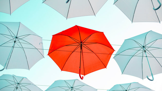 Umbrellas against the blue sky. White, yellow and red umbrella