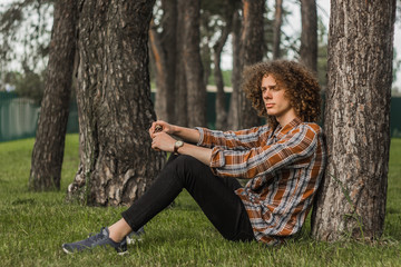 Obraz premium portrait of a young curly-haired guy in a summer park on the street. student and young traveler concept