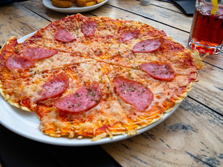 Rustic pizza with mozzarella cheese, salami, spices. Home made food. Concept for a tasty and hearty meal, on wooden background, selective focus Close up.