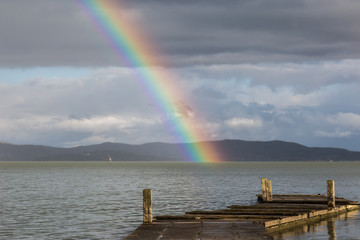 Naklejka na ściany i meble Beautiful view of a rainbow over a pier on a Trasimeno lake (Umbria, Italy)