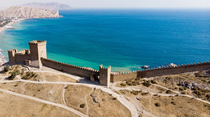 Obraz premium Architectural landmark, sight Of Crimea. Genoese fortress in Sudak. Aerial view of the ruins of an ancient castle or fortress on a mountain by the sea. Beautiful summer tourist landscape 