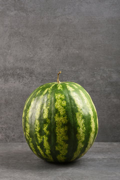 A whole watermelon on gray stone texture