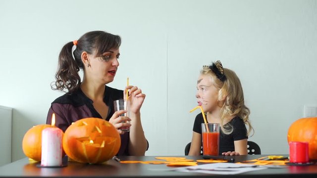 Little Girl with her Mother Having Fun while Preparing Decorations for Halloween. Young Woman Telling Scary Stories to her Cute Child. Slow Motion. Halloween Holiday Concept