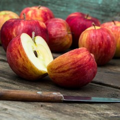 Red apple sliced and knife on old wooden table