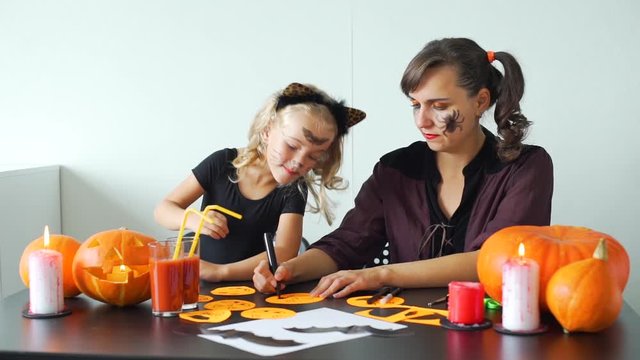 Little Girl with Mother Making Crafts from Colored Paper for Halloween at Home. Holidays and Halloween Decorations Concept