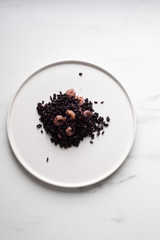 Black Italian rice Nerone in white plate on marble background with copy space