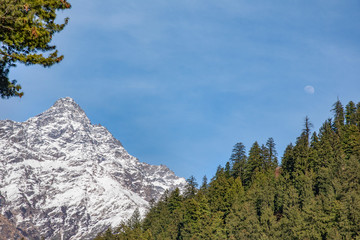 snow and green mountains with moon at blue sky