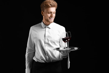Handsome waiter with wine on dark background