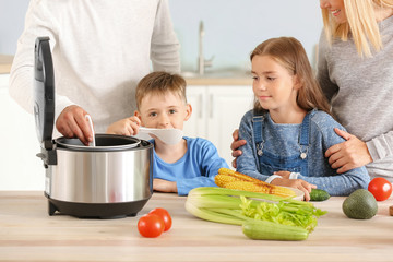 Happy family using modern multi cooker in kitchen