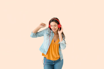 Obraz premium Young woman with headphones dancing against light background